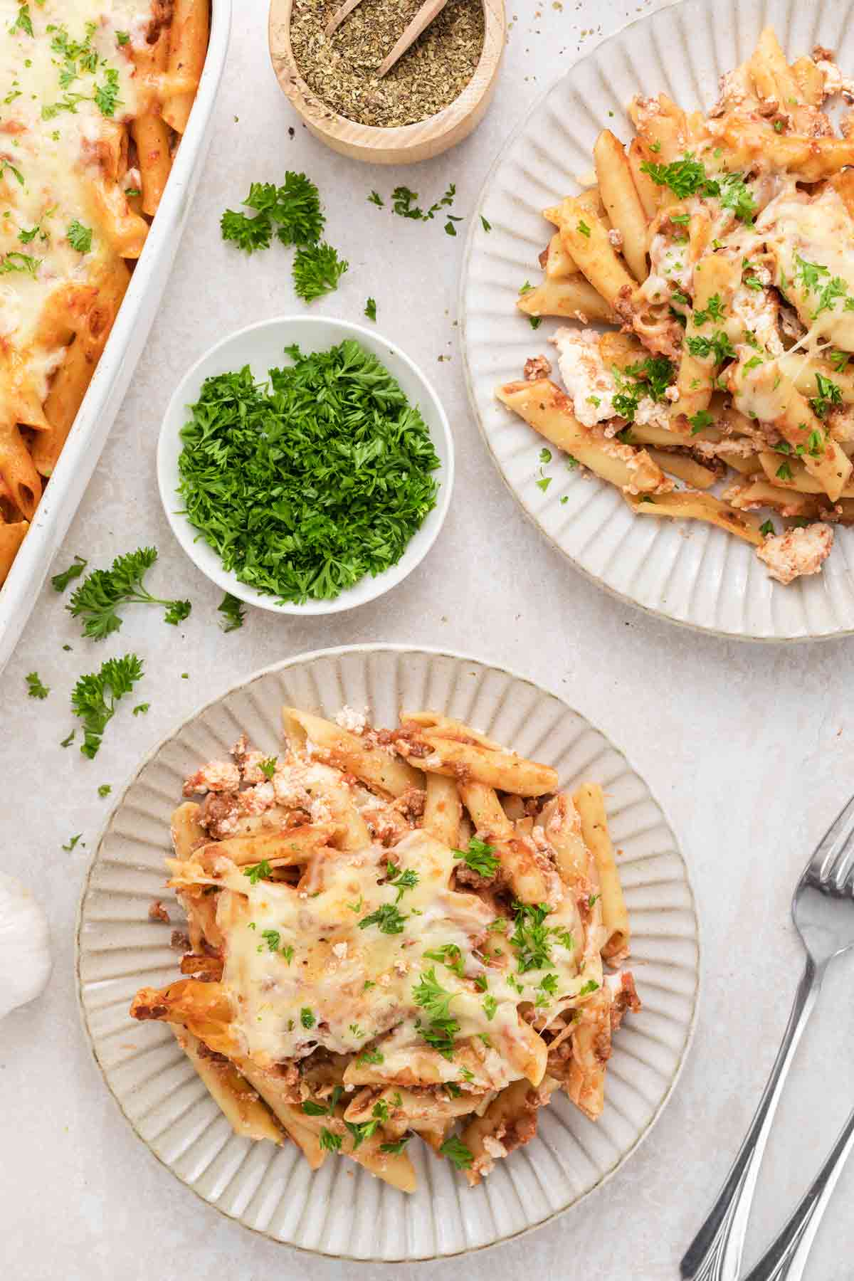 Creamy baked pasta with cheese and herbs, served on rustic plates, garnished with fresh parsley.