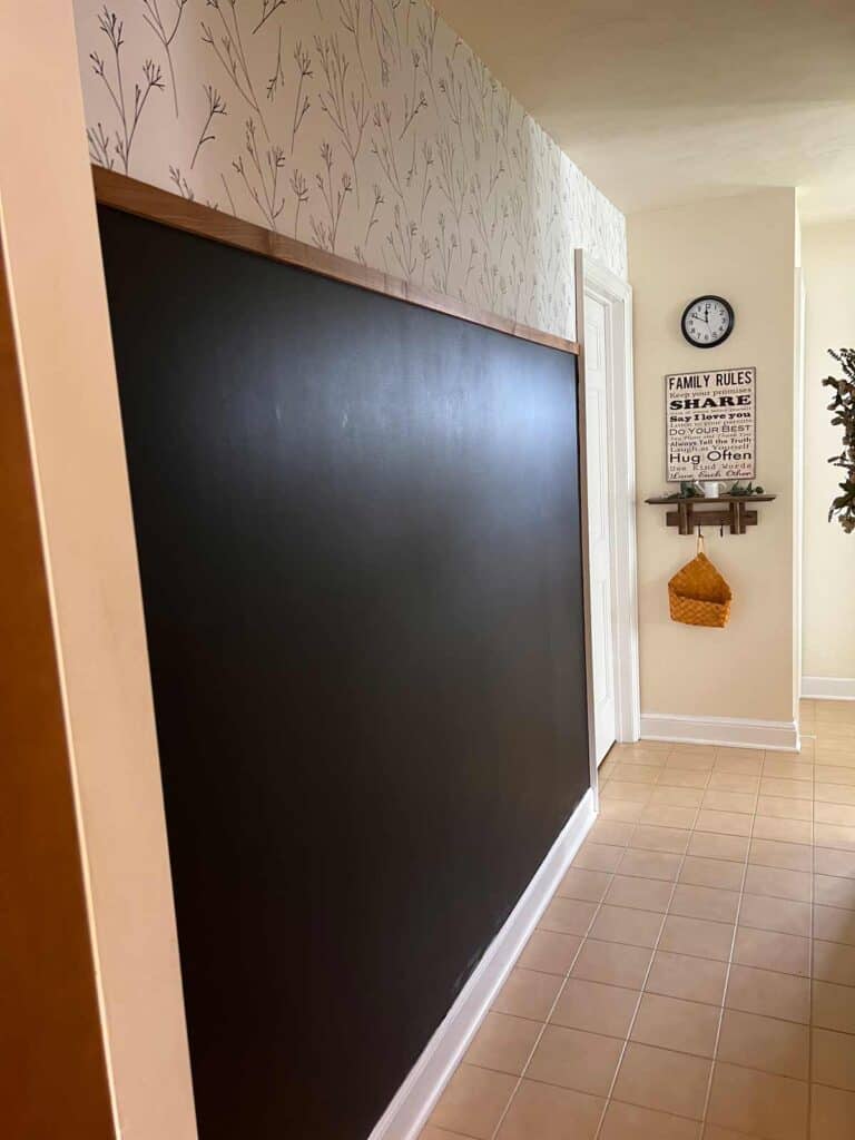 Chalkboard wall in hallway with wallpaper and wood trim