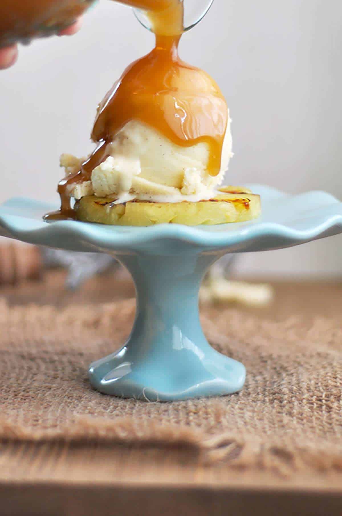 Grilled Pineapple with Ice Cream Rum Sauce Being Poured On Top